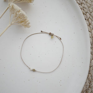 Detailfoto Armband Riverstone: gewachstes Band mit weißem Stein und Metallelement