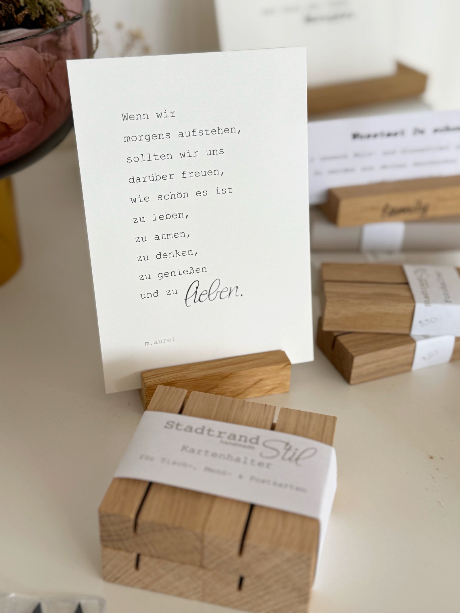 Drei Reihen mit hintereinander stehenden Platzkarten mit Namen in kleinen Kartenhaltern aus Eichenholz. Davor liegt ein Zweig Eukalyptusblätter