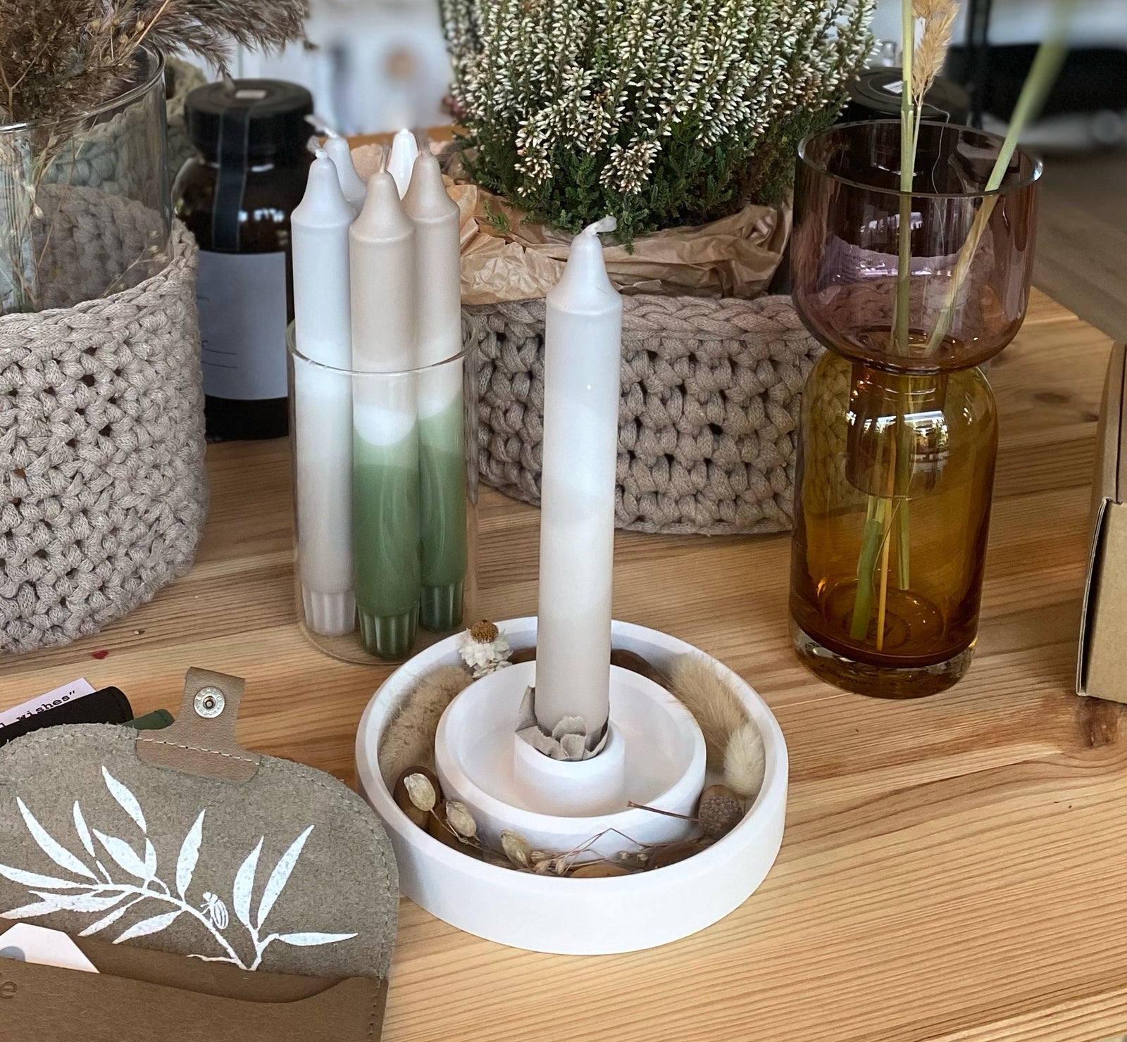 Weißer Kerzenständer, alch mit doppeltem Rand und einer weißen Kerze mit schwarzen Herzen sowie getrockneten Mohnkapseln