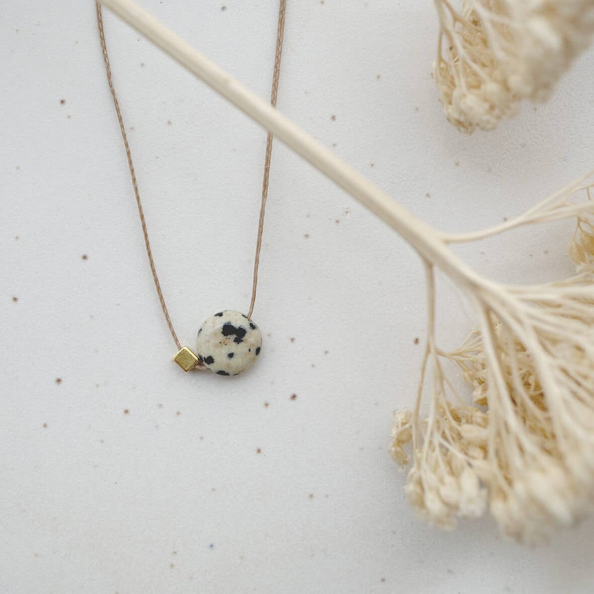 Detailansicht einer Kette: Dalmatiner Jaspis mit Messingelement an gewachstem Band 