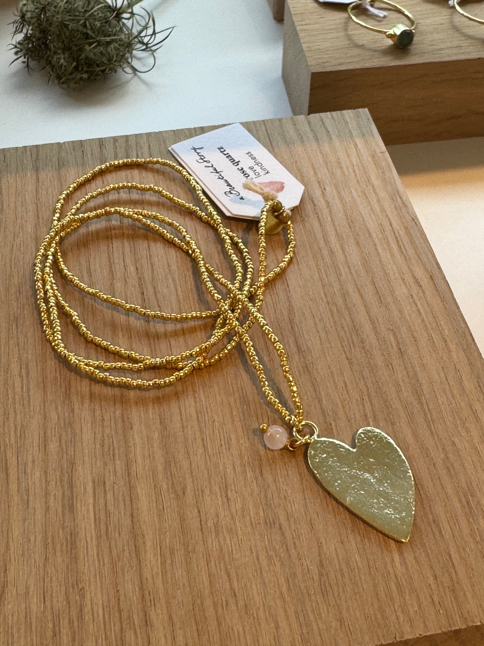 Goldfarbene Kette aus Glasperlen mit Gold Herz auf Holzplatte