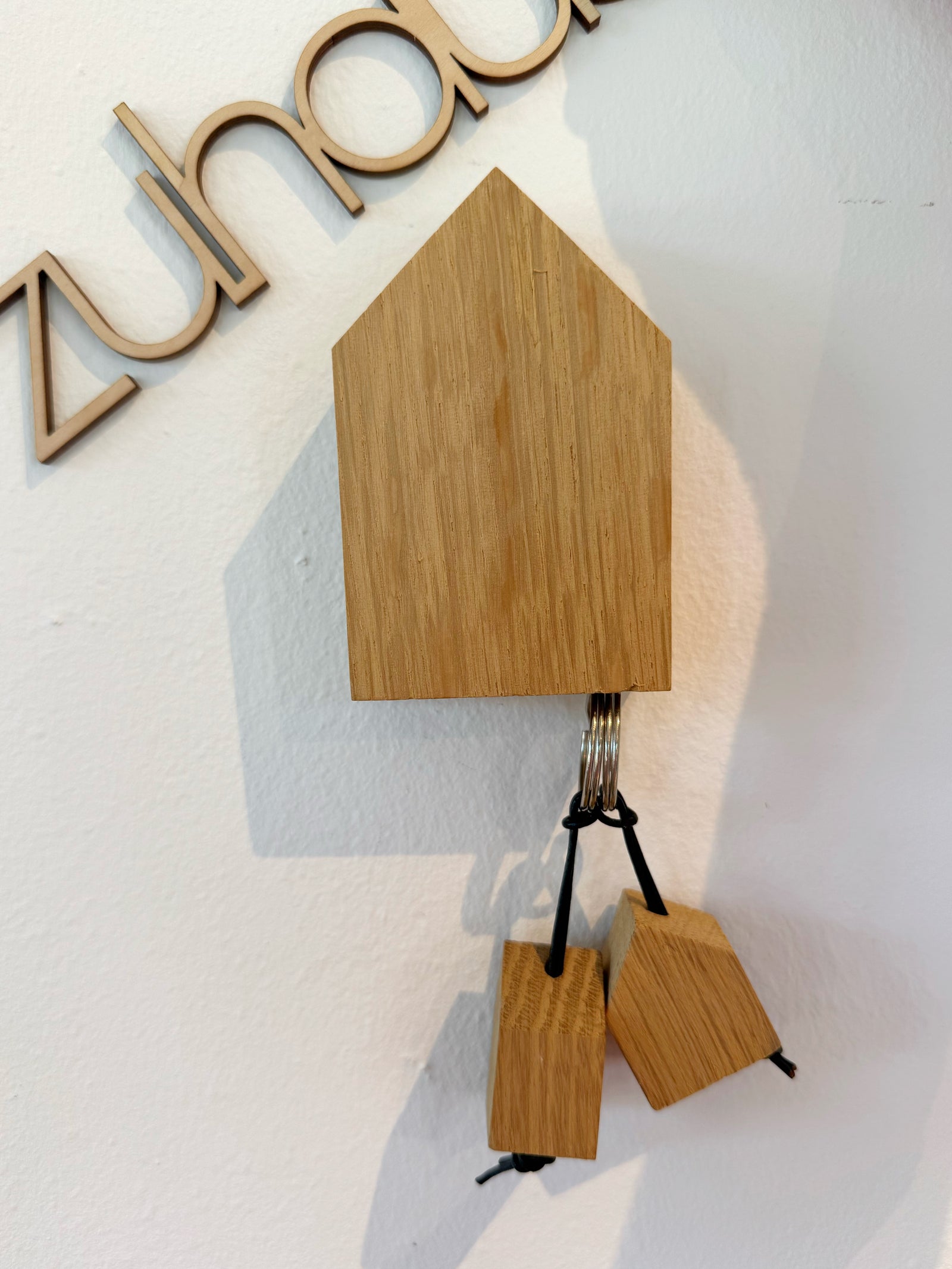 Holzhaus, das an der Wand hängt und durch eingelassene Magnete als Schlüsselbord dient