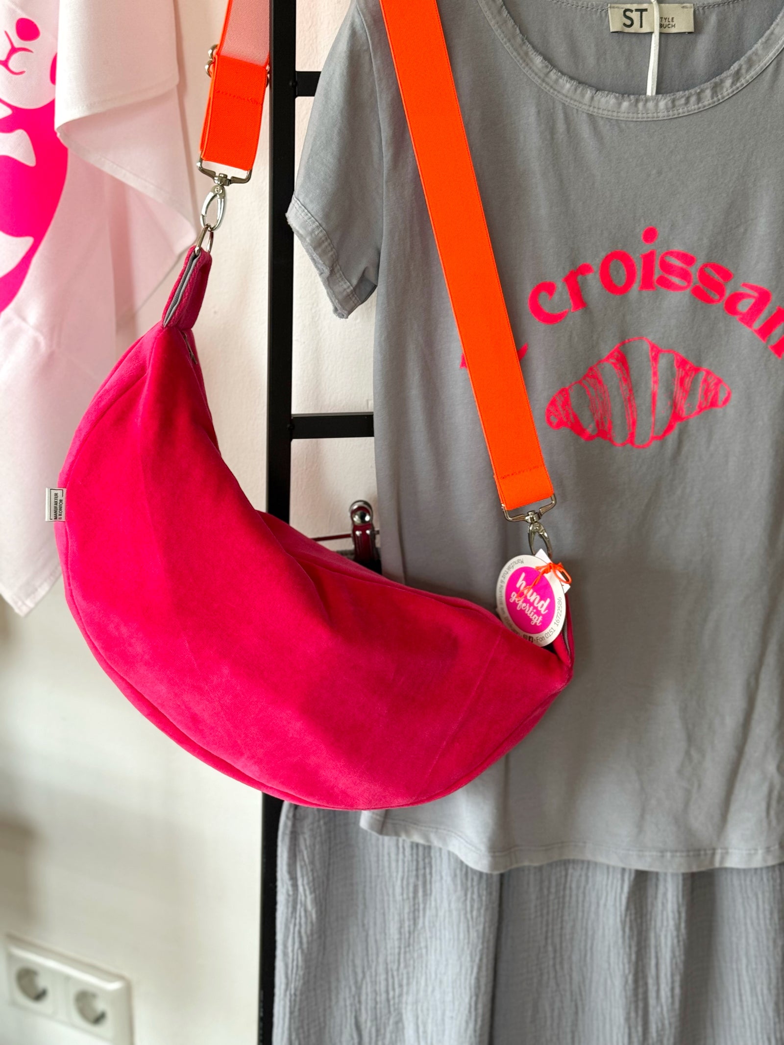 Pinke Crossbodybag aus Ncky mt orangenem Neon Gurt mit grauem T-Shirt mit Neon Druck Croissant