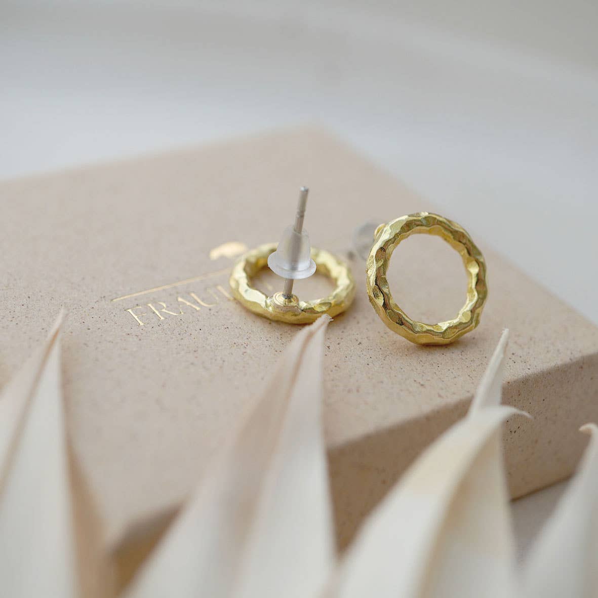 Ohrstecker rund, strikturierte Oberfläche, goldfarben auf Schmuckschachtel