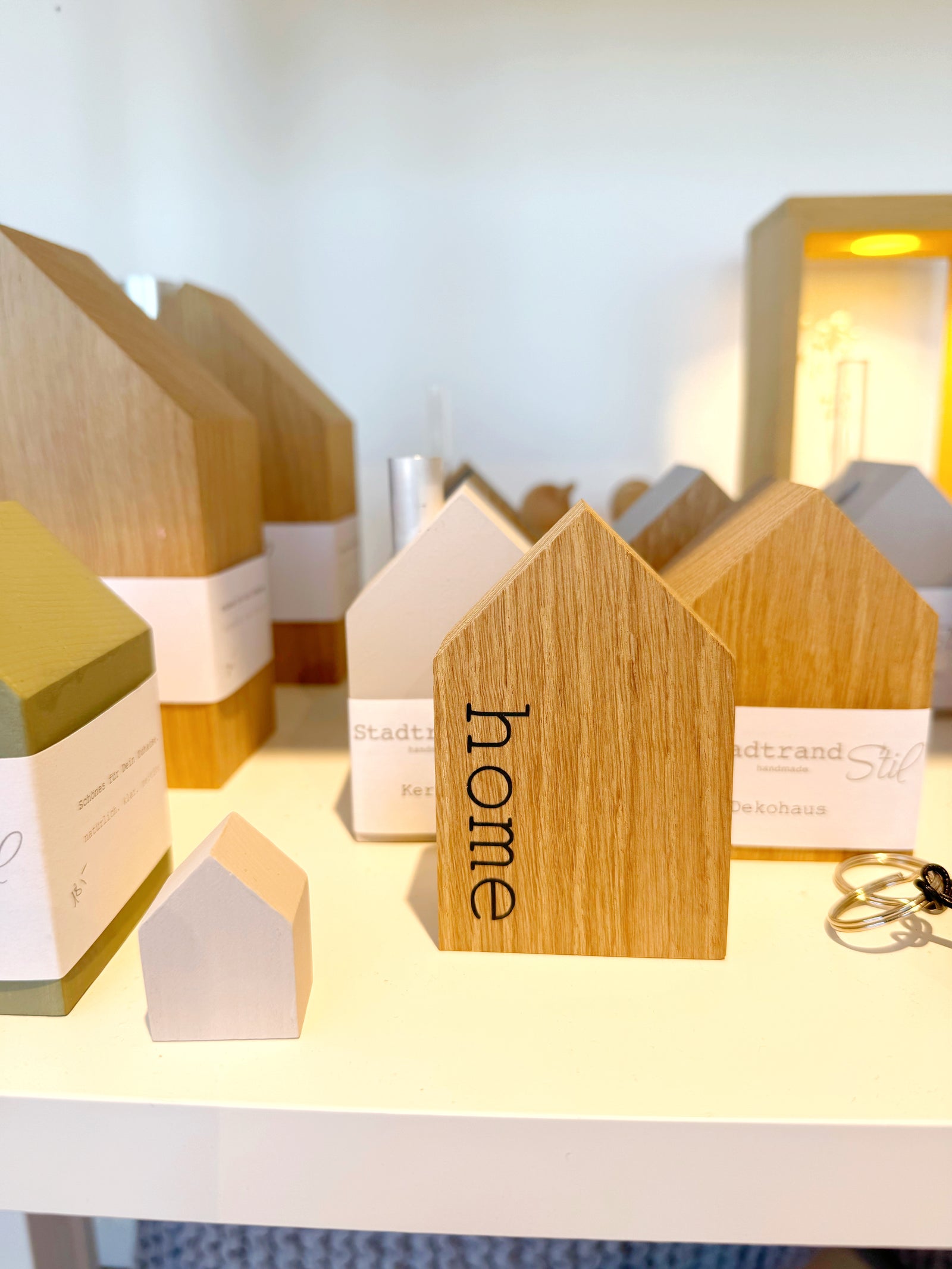 Dekohaus aus Eiche mit aufgedrucktem "home" zwischen anderen Holzhäusern von tadtrand Stil handmade