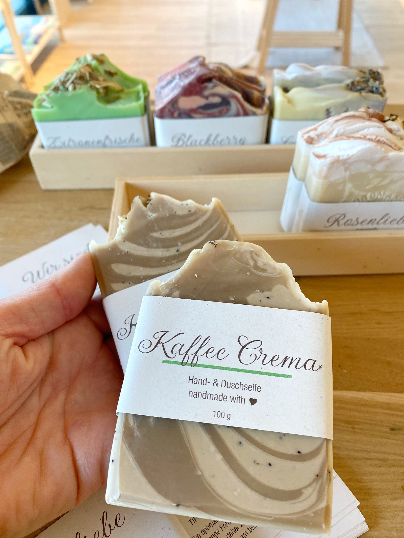 vier handgemachtse Seifen in verschiedenen Düften mit Papierbanderole in einer Holzkiste