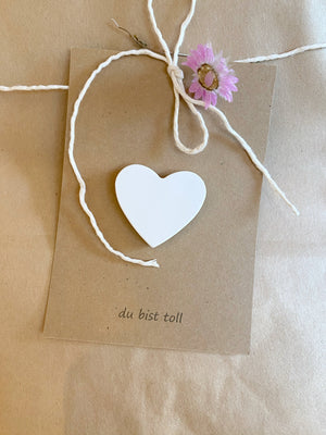 Geschenkanhänger mit weißem Rysierz und dem Audruck "di bist toll" . Angebracht an einer Kraftpapiererpackung, natürlich dekoriert mit Strohblume