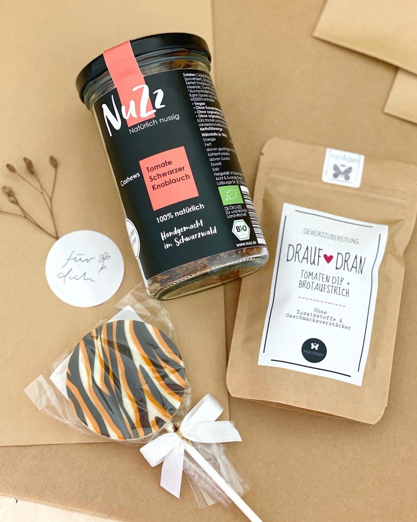 Geschenktüten aus Kraftpapier, natürlich dekoriert, darauf ein Glas Gewürznüsse, eine Tüte mit Gewürzmischung und ein Schokoladen Lolli im Zebramuster. Conceptstore Stadtrandstil