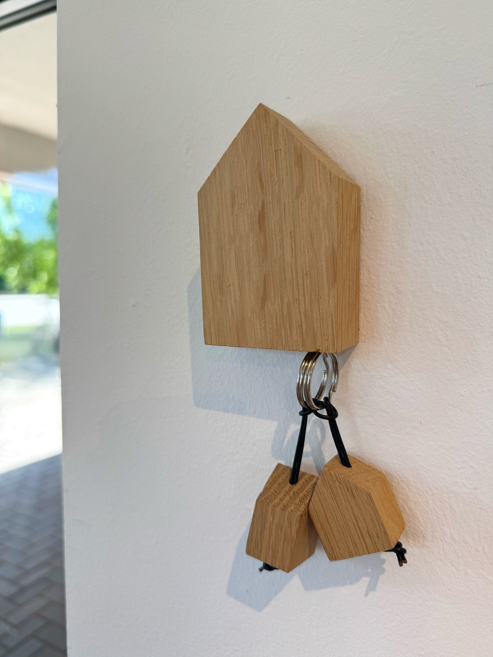 Holzhaus, das an der Wand hängt und durch eingelassene Magnete als Schlüsselbord dient