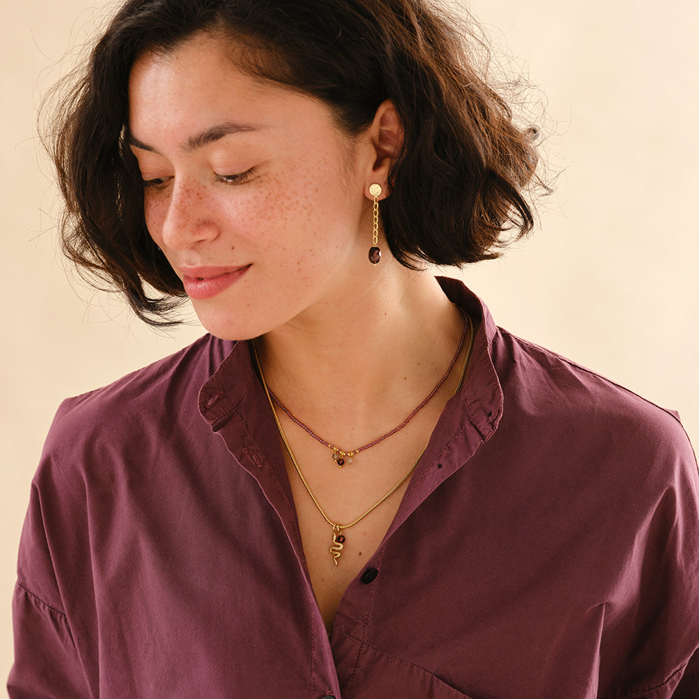 kette mit brombeerfarbenen Glasperlen und Rosenquarz auf Holzplatte