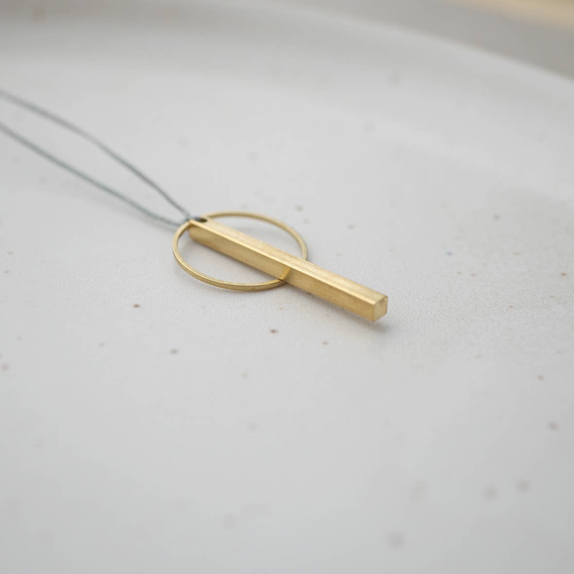 Detailaufnahme Kette: minimalistische Anhänger golfarben ein Ring und ein Rechteck an Band