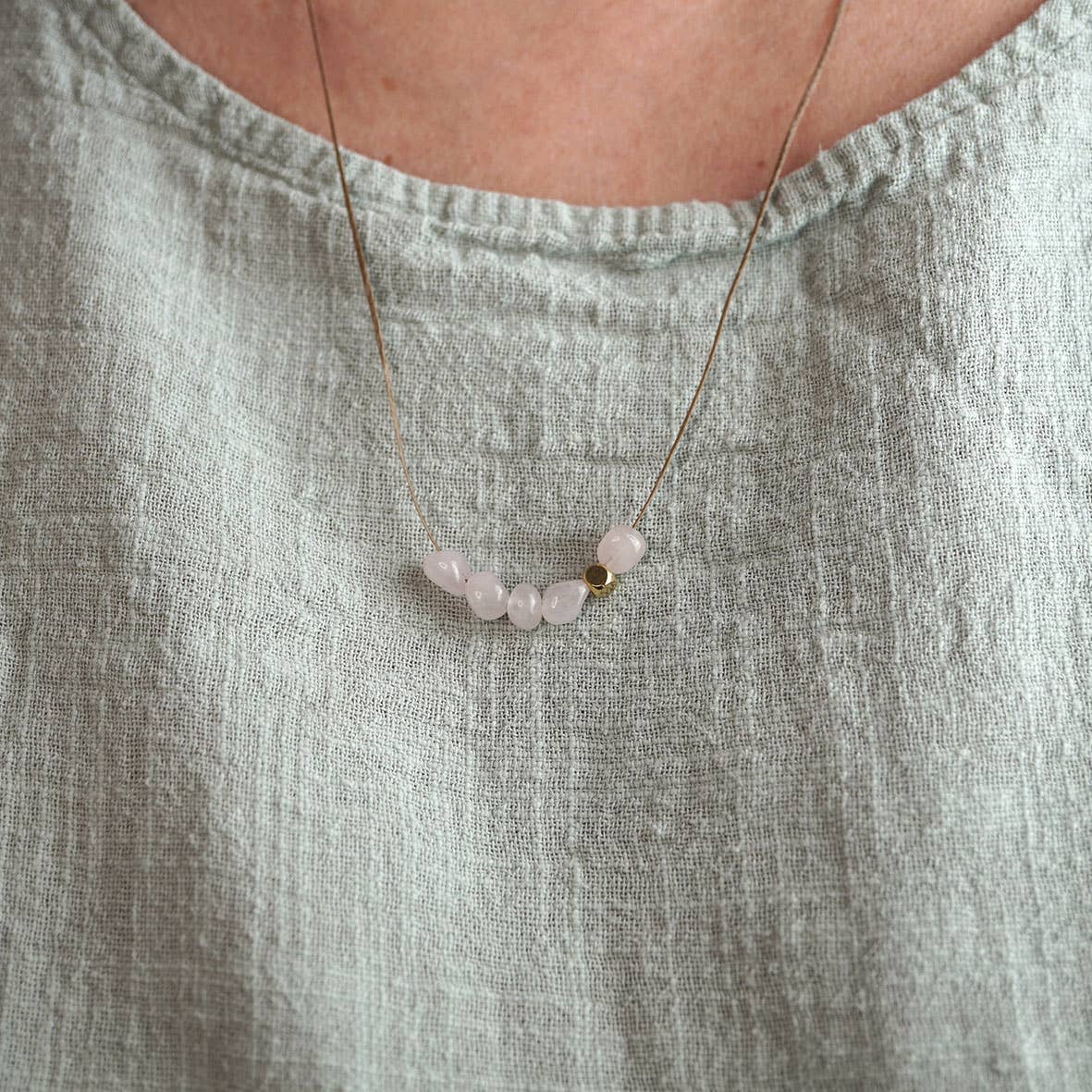 Detailfoto Kette Nala: gewachstes Band mit 5 Rosenquarzperlen und einem goldfarbenem Metallelement