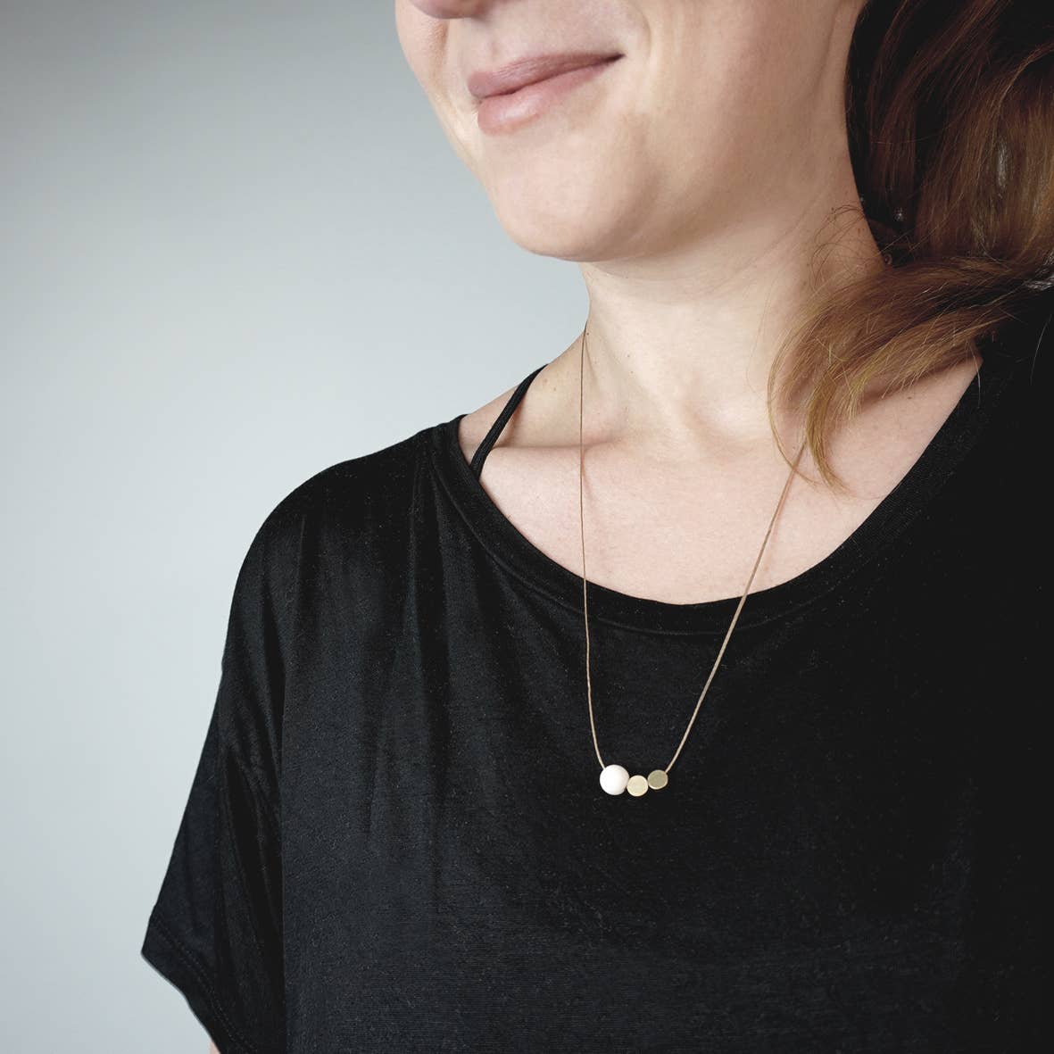 Detilfoto kette riverstone von Fräulein Tapir: gewchstes Band mit zweo Metallscheiben und einer weißen Kugel als Anhänger