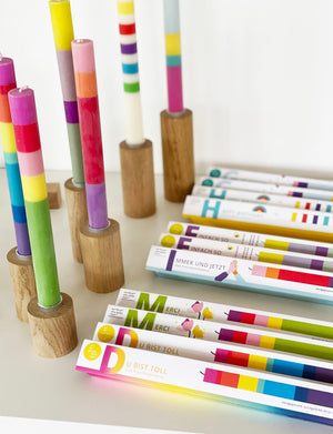 Bunte, gestreifte Kerzen von not the girl, teilweise in Kerzenständern von Stadtrandstil, teilweise in Verpackung mit Spruch
