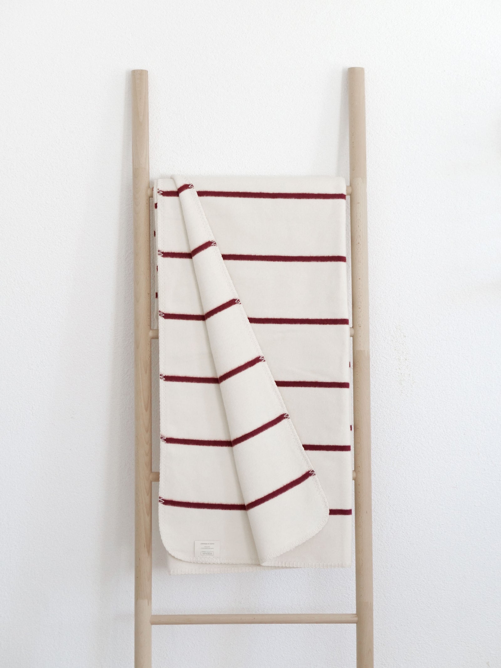 Wollweiße Decke mit roten Streifen, dekoriert mit einem weißen Lichterhaus