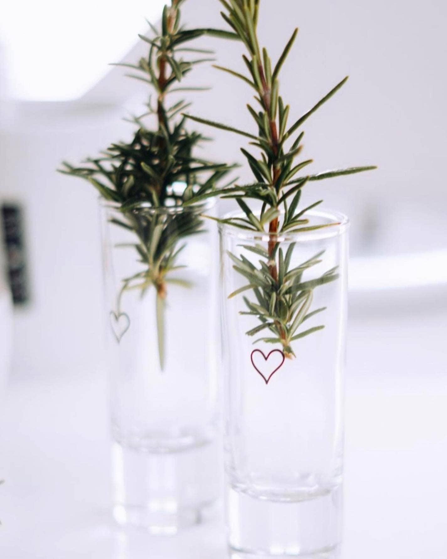 Schnapsglas mit Herz, das als Vase genutzt ist. Gefüllt mit Trockenblumen und einer Holzblume