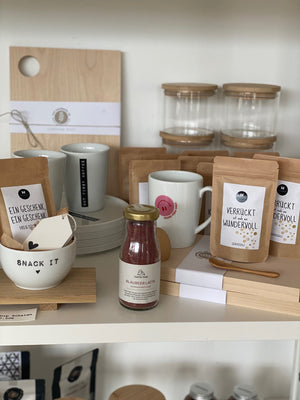 Regalarrangement im Conceptstore Stadtrandstil mit Küchen Geschenken, wie Kräutermischungen, Vorratsgläsern, Servierbrettern, Tassen. Alles im natürlichen Look