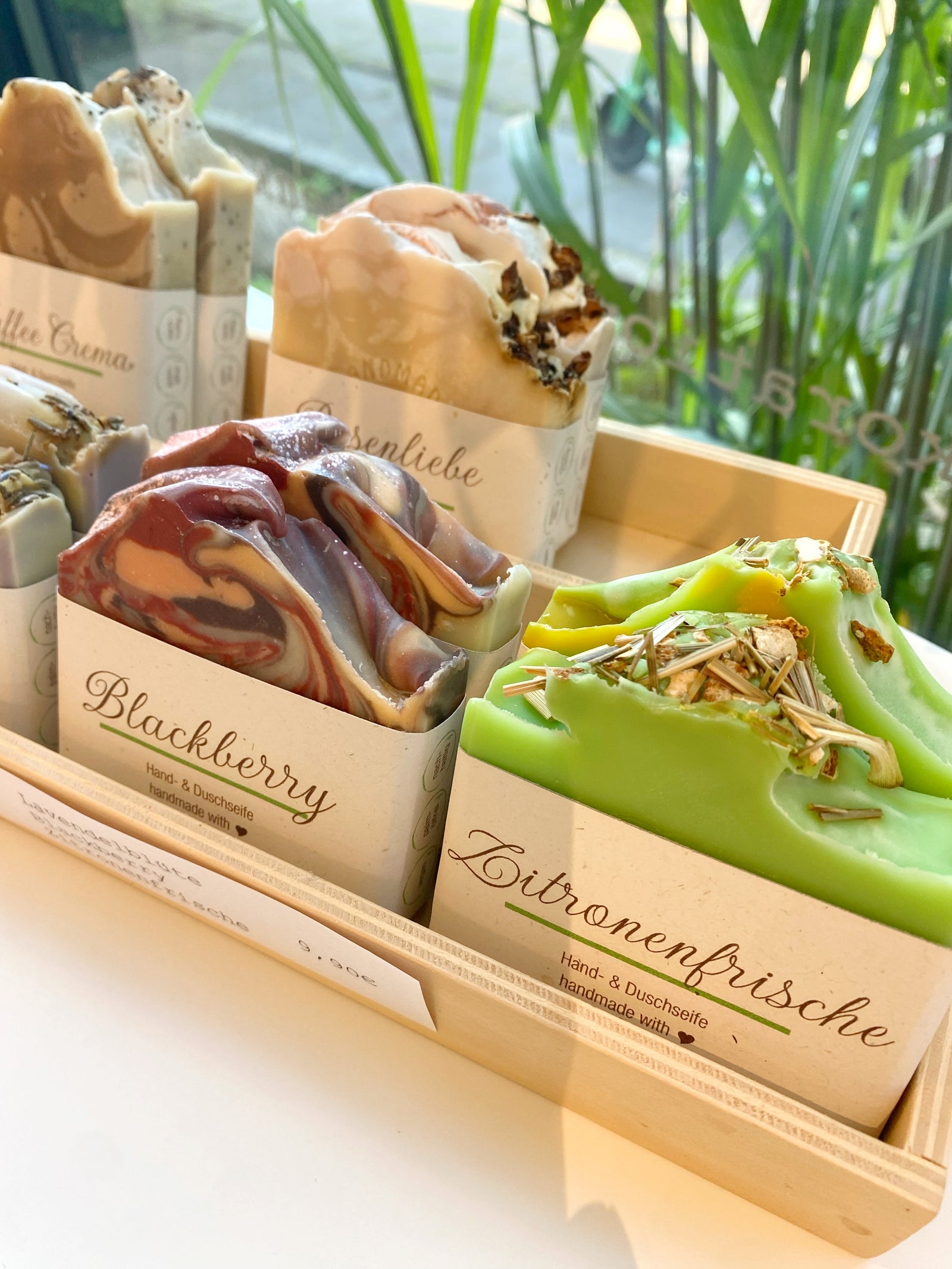 vier handgemachtse Seifen in verschiedenen Düften mit Papierbanderole in einer Holzkiste