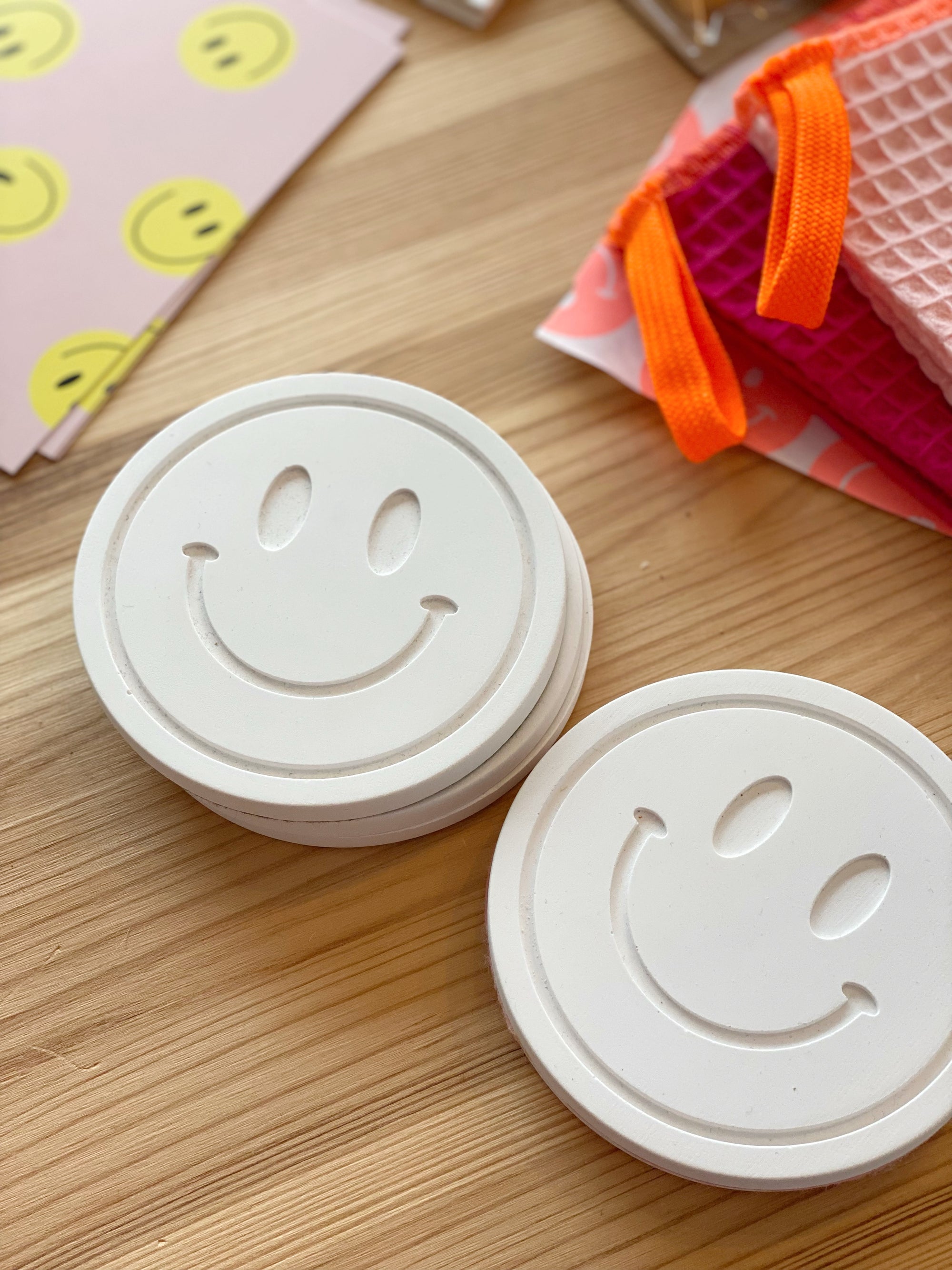 Zwei weiße runde Untersetzer in Forn eines Smileys aus Raysin