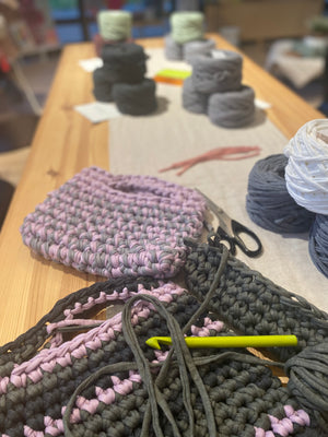 Tisch mit Garn und fertigen, gehäkelten Taschen eines workshops