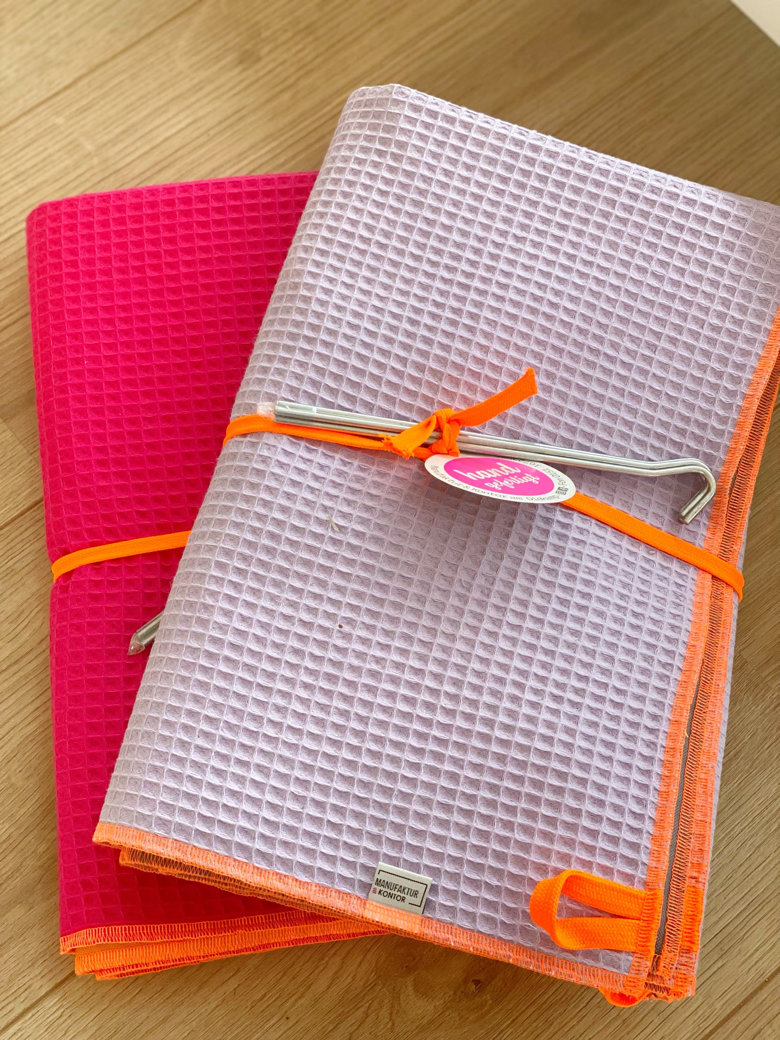 zusammengelegte Strandtücher in flieder und pink aus Waffelpikee mit zwei Heringen