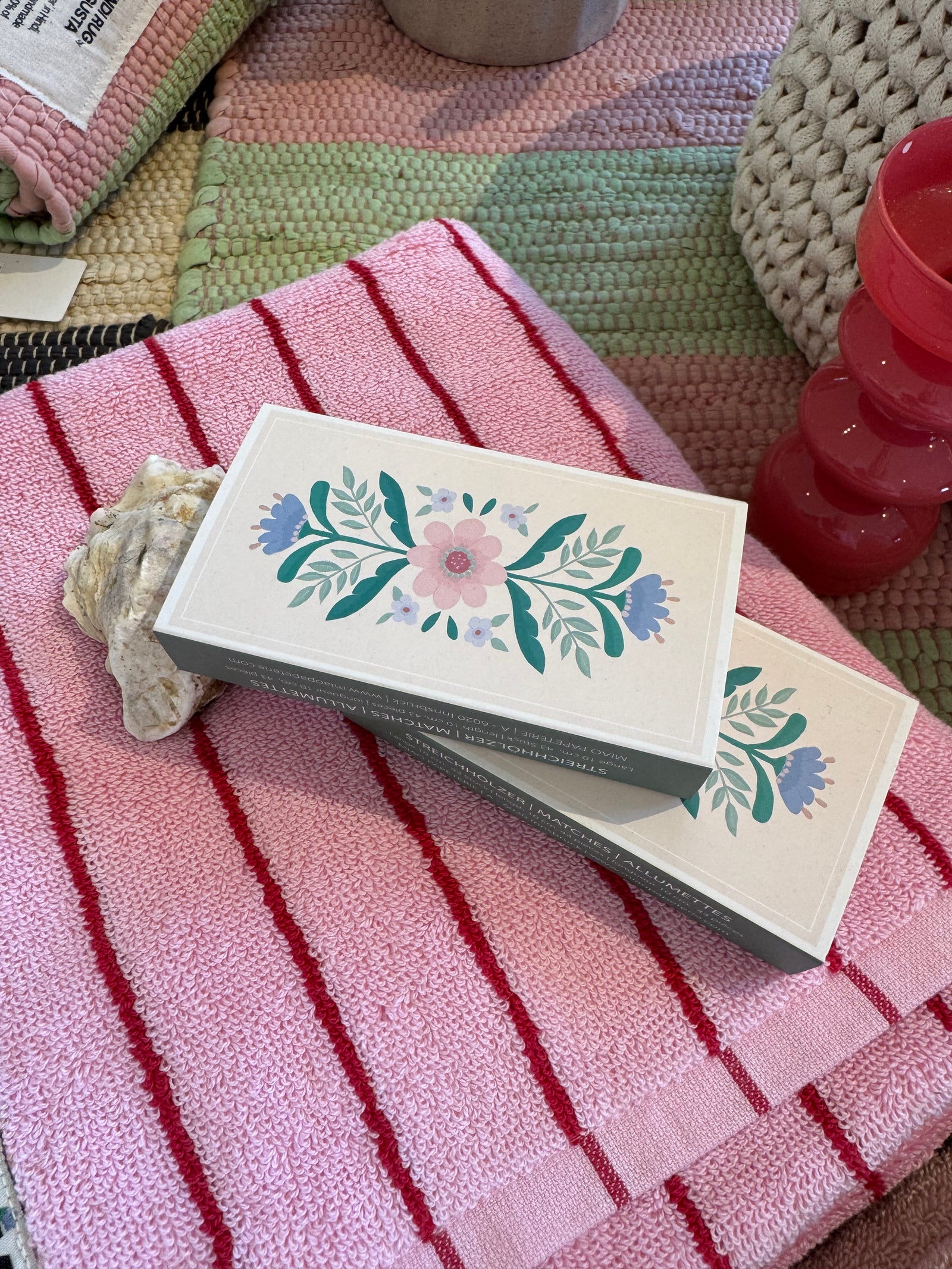 streichhölzer mit blumenmotiv auf rosa rot gestreiftem Handtuch