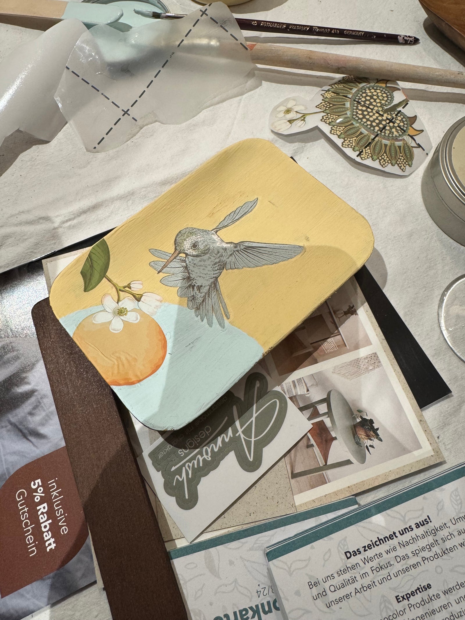 Holzschale von Teilnehmerin gestaltet mit Vogel und Orangen auf Arbeitstisch. Impression Workshop Holzschale