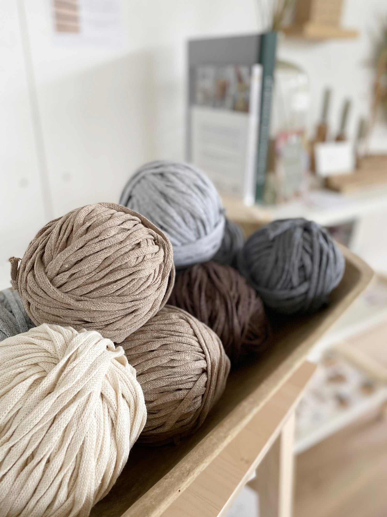 Mehrere Knäuel naturfarbenes Garn in einer Holzmole.