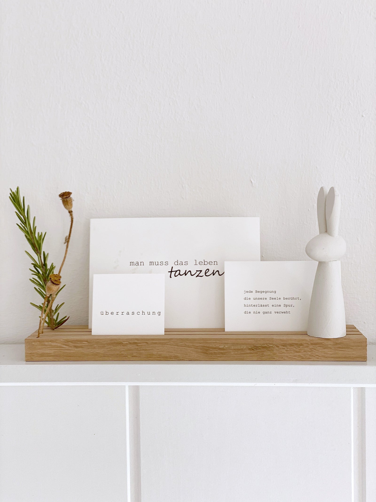 Großer Fotohalter mit drei Rillen von Stadtrandstil. Dekoriert mit einer Postkarte mit dem Aufdruck Glücksmomente und einer A5 Karte mit Text. Davor eine Minivase mit Trockengras.