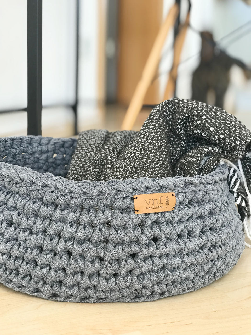 Großer Strickkorb in betongrau von Stadtrandstil, in dem eine dünne Decke liegt