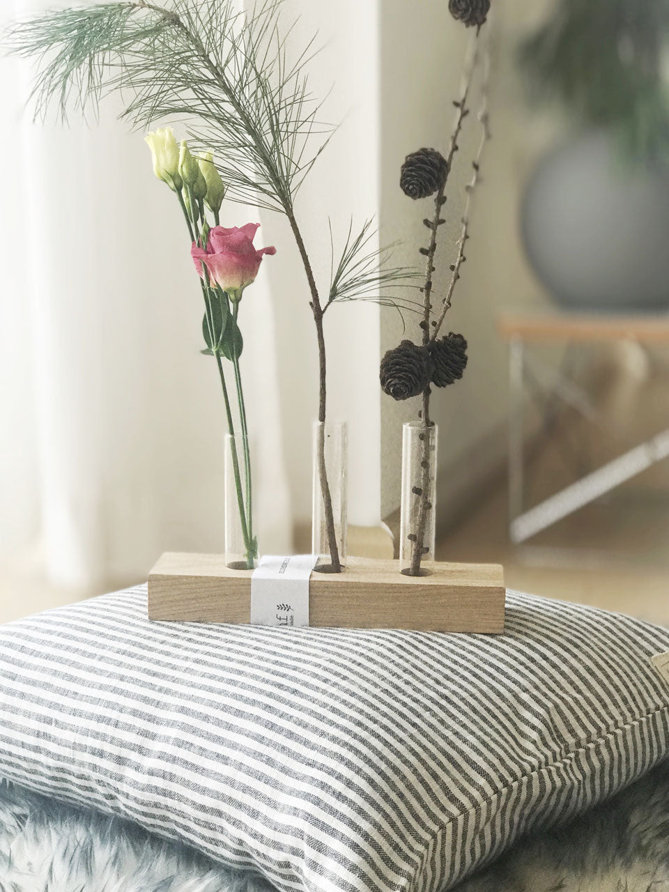 Blumenwiese; Blumendisplay mit drei Gläsern gefüllt mit Eukalyptus und Trommelstöcken, daneben ein kleines, gelbes Stricktuch und eine Schere