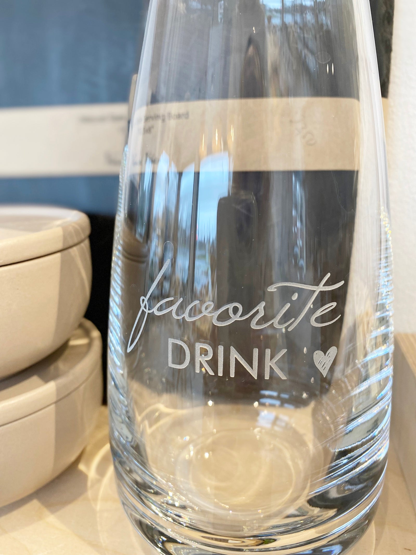 Teilansicht einer Glaskaraffe mit dem grvierten Text "favorite drink" und einem Herzen