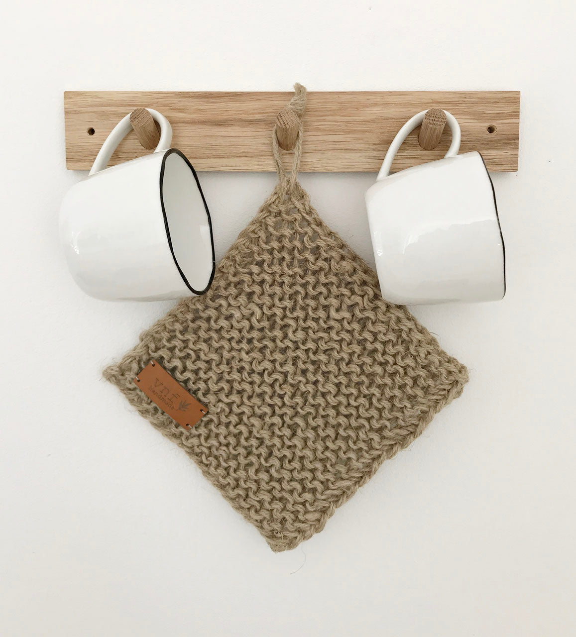 Hakenleiste aus Eiche mit drei Haken, an denen zwei weiße Tassen und einem Untersetzer aus Jute hängen