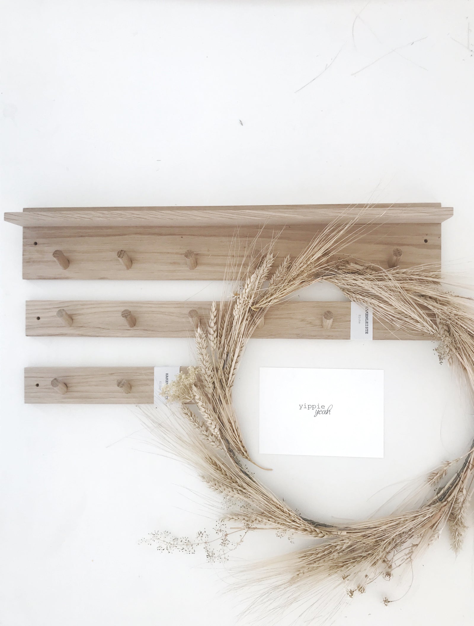 Seitenansicht auf eine lange Hakenleiste aus naturbelassener EIche an der ein Schlsselanhänger, eine Schere und ein Untersezer aus Jute hängen