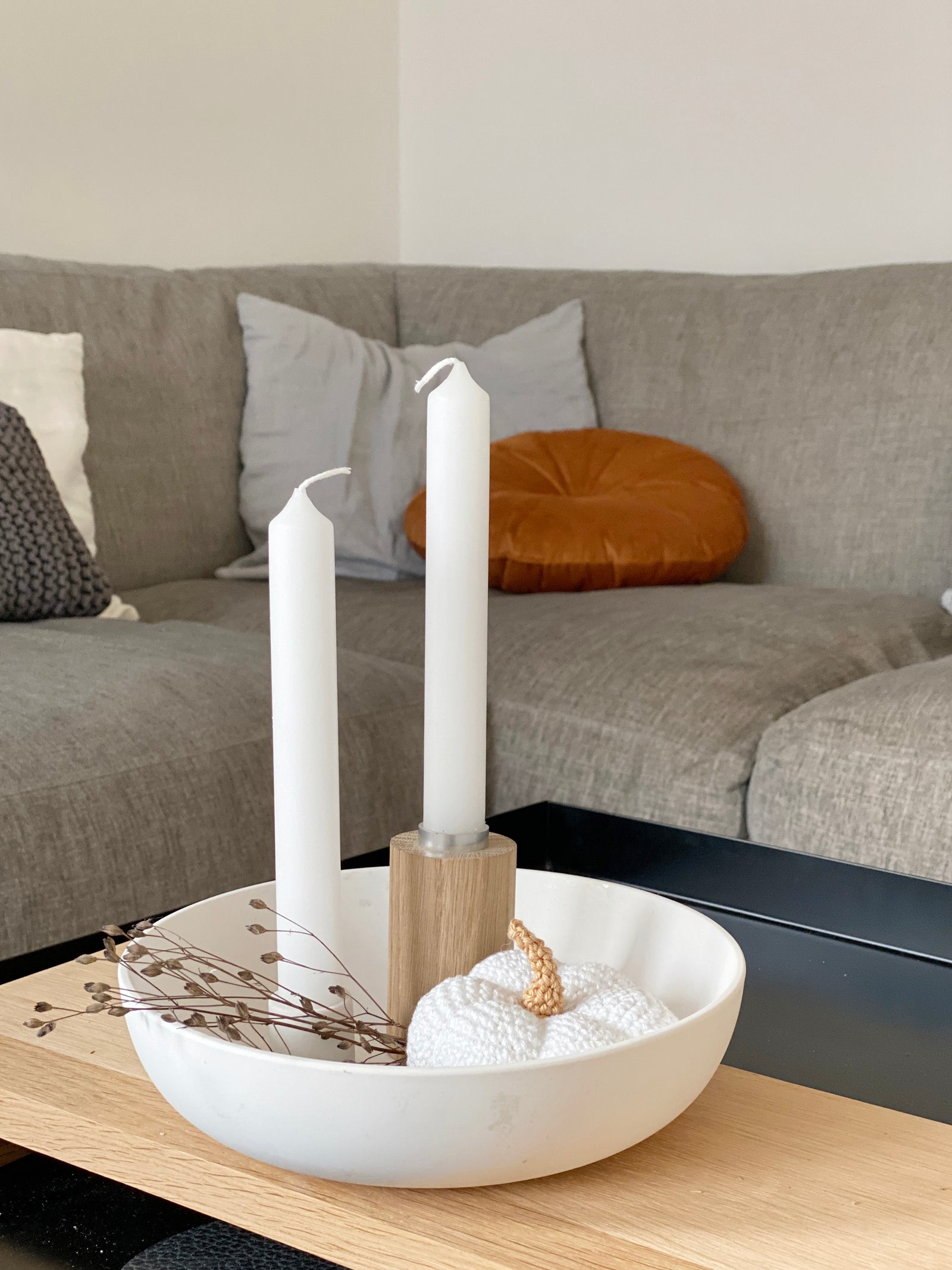 Zwei runde Kerzenständer aus Eiche in zwei Größen und mit weißen Kerzen stehen auf einem Eichentisch. Daneben eine weiße Schale auf Fuß, gefüllt mit einer getrockneten Hortensienblüte
