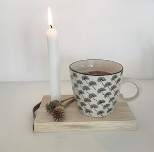 Kleines Tablett mit Kerze und schwarz-weißer Kaffetasse und getrockneten Mohnkapseln