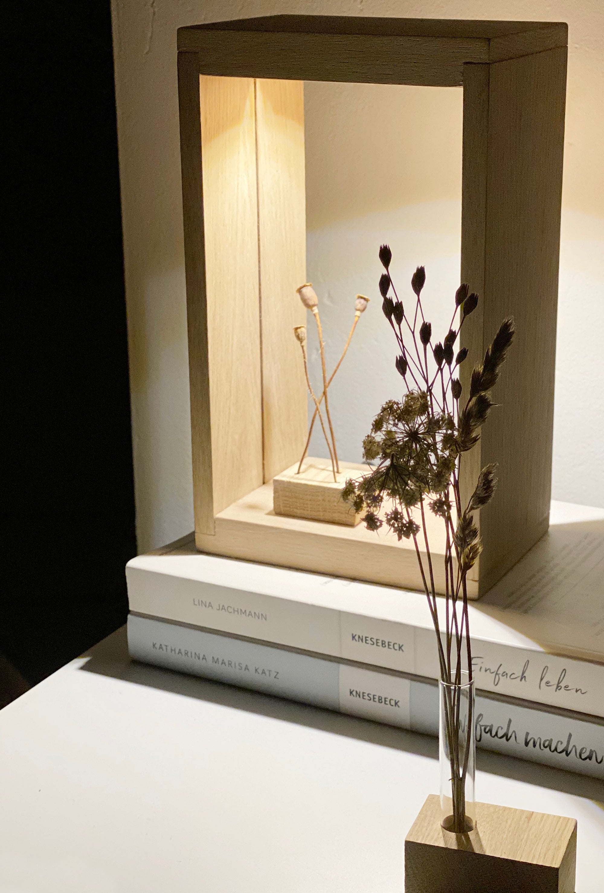 Stimmungsvolles Licht mit der Lampe frame, einem indirekt beleuchteten, rechteckigen Dekorahmen. Darin steht eine Minivase mit kleinen Mhnkapseln