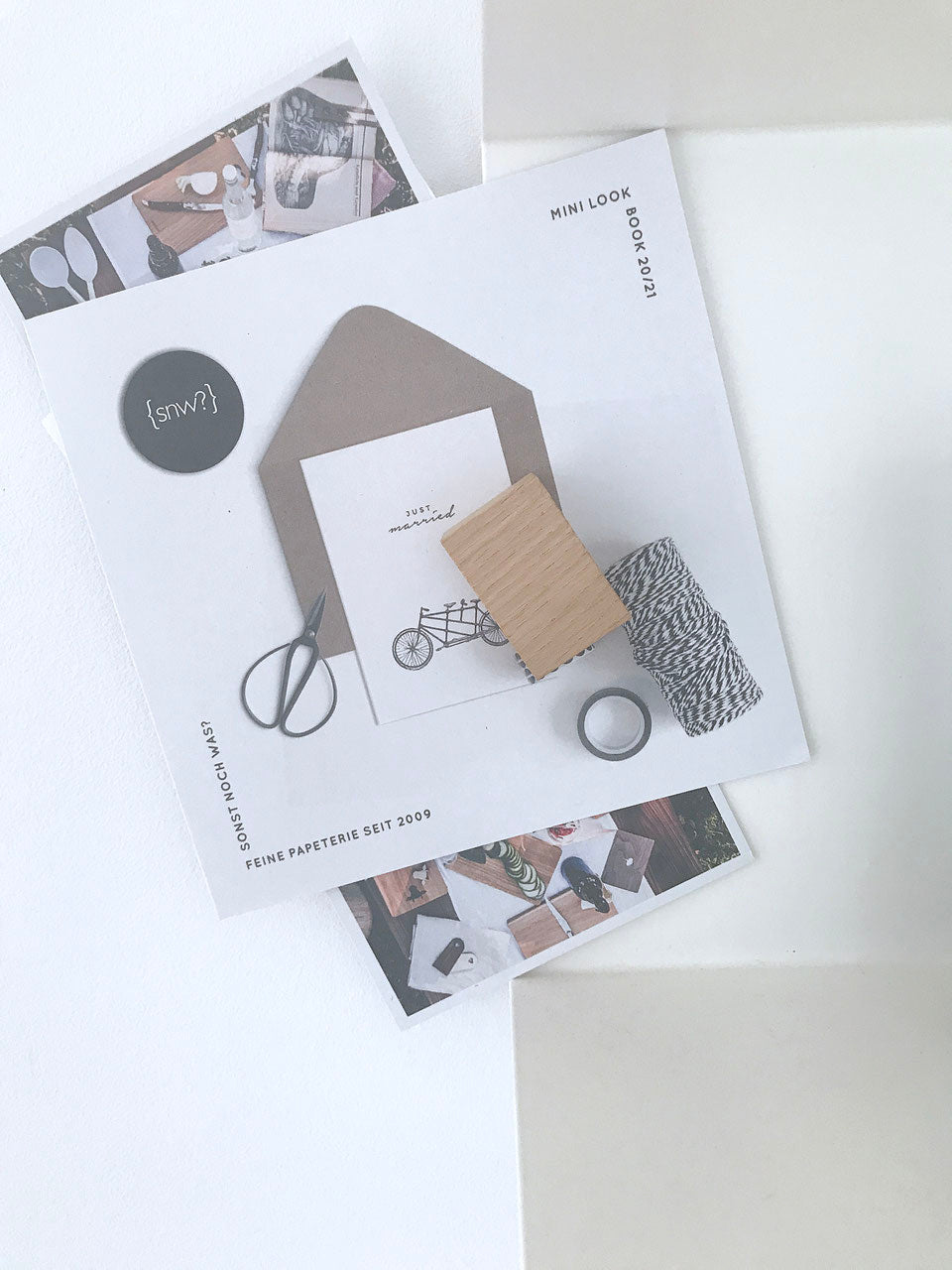 Zwei Magnethalter aus Eiche halten eine Postkarte. Dahinter eine schwarze Kugelvase mit weißen Tulpen und ein paar Bücher