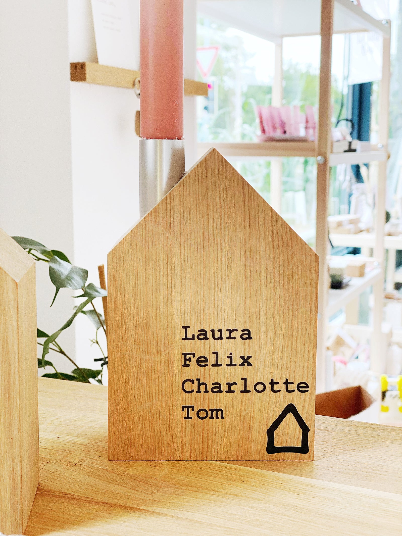 Ein großes Kerzenhaus von Stadtrandstil, mit vier untereinanderstehenden Namen und einem stilisiertem Haus. Beispiel für eine Personalisierung