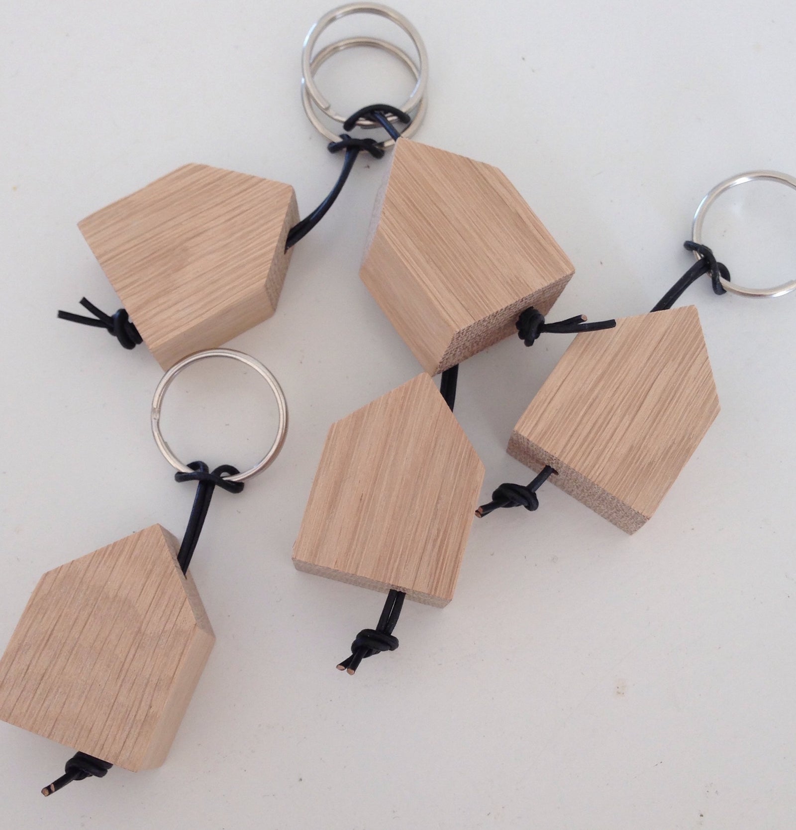 fünf Schlüsselanhänger mit stilisiertem, kleinen Haus aus Eiche, schwarzem Lederband und Schlüsselring in silber