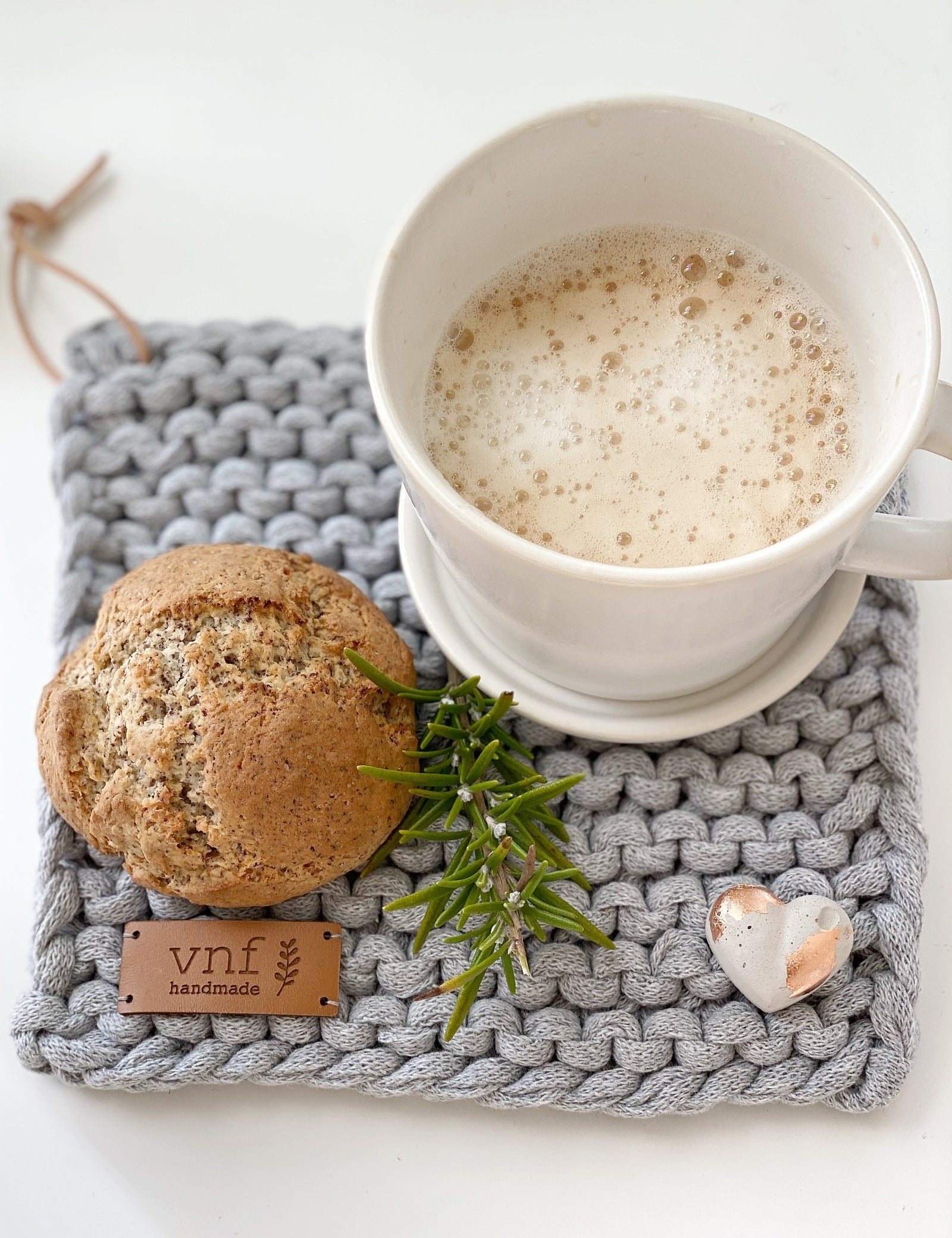 Eichenleiste mit Ablage an der vier gestrikte Untersetzer hängen. Auf der Ablage stehen minimalistische Hasen und drei Minihäuser. Alles von Stadtrandstil handmade